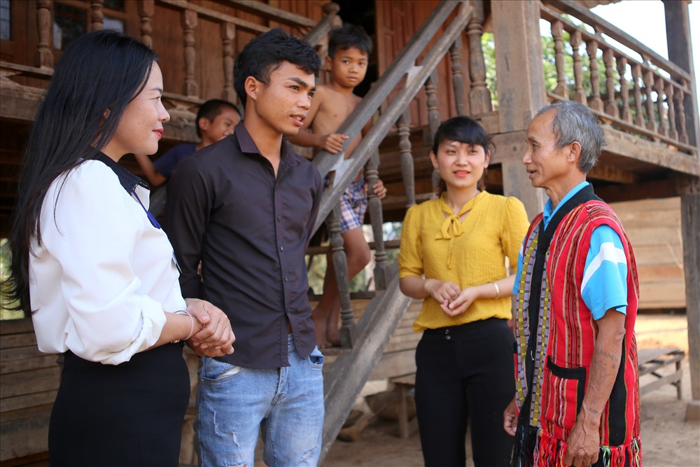 Cô Nguyễn Thị Thủy - Hiệu trưởng Trường Tiểu học Thanh (xã Thanh, huyện Hướng Hóa, Quảng Trị - người mang áo trắng) nhờ già làng Pả Keo vận động người thân của học sinh đến lớp ngày đầu năm. Ảnh: Hưng Thơ.