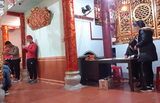 Một phụ nữ đang chờ ghi phiếu công đức tại một địa điểm nằm sâu bên trong Phủ Bóng.