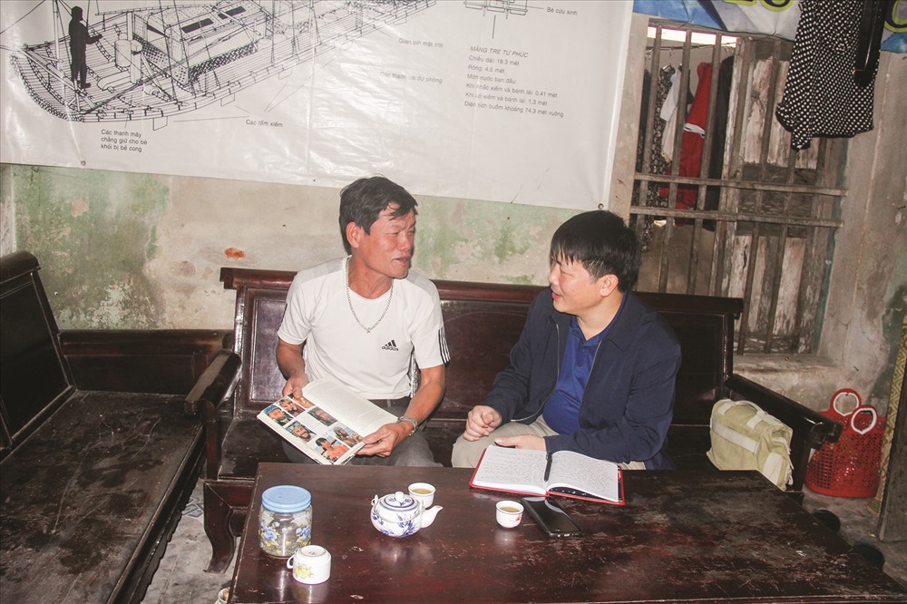 Ông Lương Viết Lợi trao đổi với tác giả trong căn nhà tồi tàn, đằng sau là bản vẽ chiếc bè huyền thoại.