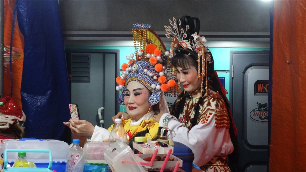 Trong phút rảnh rỗi, hai nghệ sĩ tranh thủ chụp hình trước giờ diễn, ngay giữa không gian ồn ào, lộn xộn nơi sân đình
