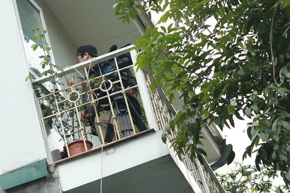 Một phóng viên lựa chọn góc trên ban công nhà dân để tác nghiệp.