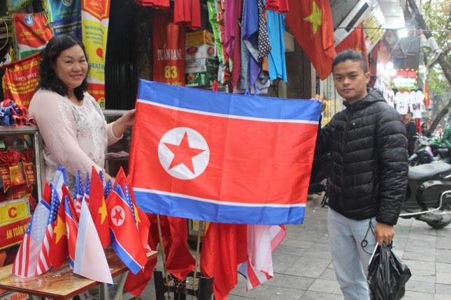 Anh Trà (lề phải), một du khách đến từ Quảng Bình chia sẻ : “ Tôi thấy rất vui khi lần này Việt Nam được lựa chọn là nơi diễn ra hội nghị thượng đỉnh Mỹ - Triều lần 2. Điều này chứng tỏ rằng hình ảnh Việt Nam đã được nâng cao trên thế giới. Nhân dịp này tôi có đến đây mua một vài lá cờ về làm kỷ niệm”.
