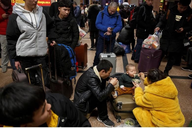 Một người phụ nữ tranh thủ cho con ăn ở ga Bắc Kinh.