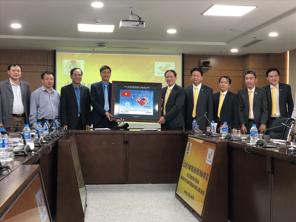 Chủ tịch HĐQT TCty Bưu điện VN Phạm Anh Tuấn trao tặng tem kỉ niệm Hội nghị Thượng đỉnh Mỹ - Triều Tiên cho Phó Chủ tịch Tổng LĐLĐVN Ngọ Duy Hiểu (trái). Ảnh: VH