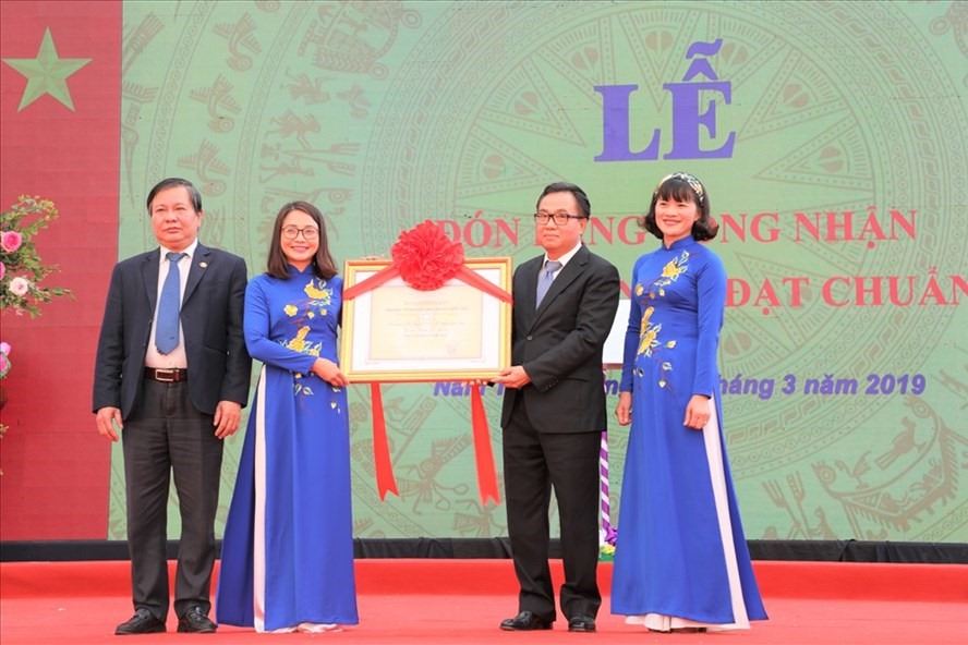 Cô Nguyễn Thị Lý đại diện cho giáo viên và học sinh của nhà trường nhận bằng công nhận Trường THCS Nguyễn Du đạt chuẩn quốc gia.