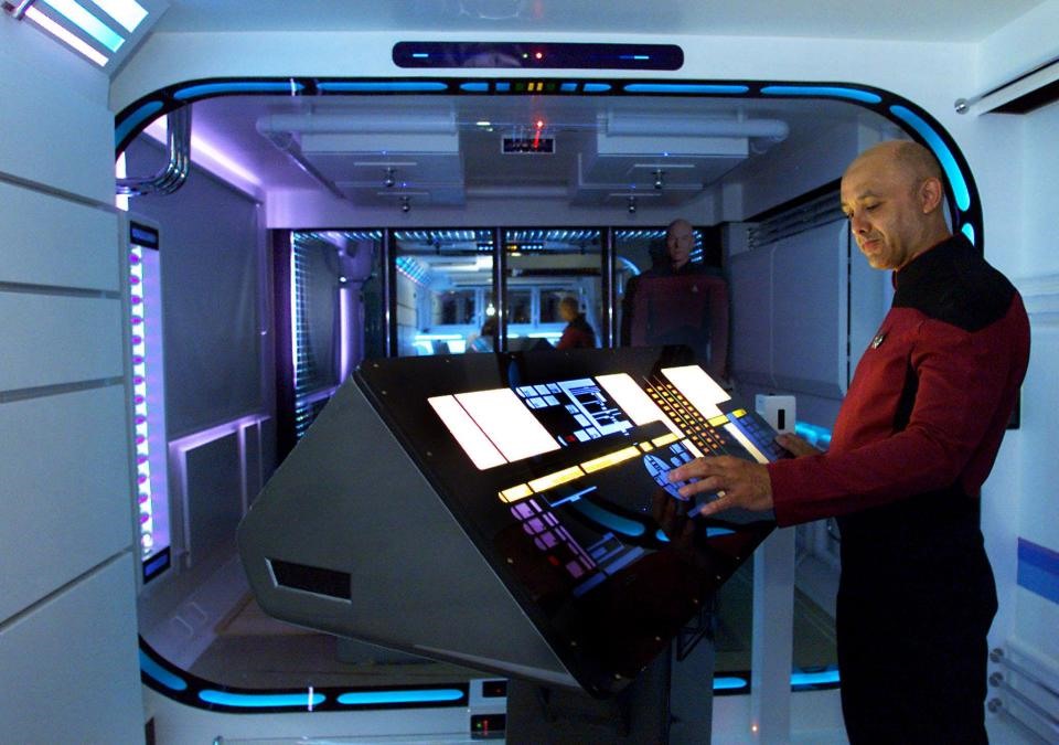 Người chủ trước tự hào đứng trước bàn điều khiển trong bộ đồng phục Star Trek của mình.