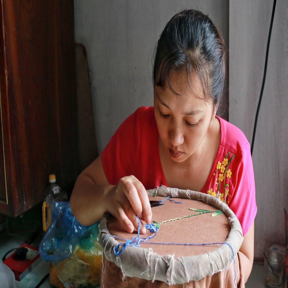 Chị Mai Thị Hải đang thêu các họa tiết trên áo dài giúp cho sản phẩm bắt mắt hơn.