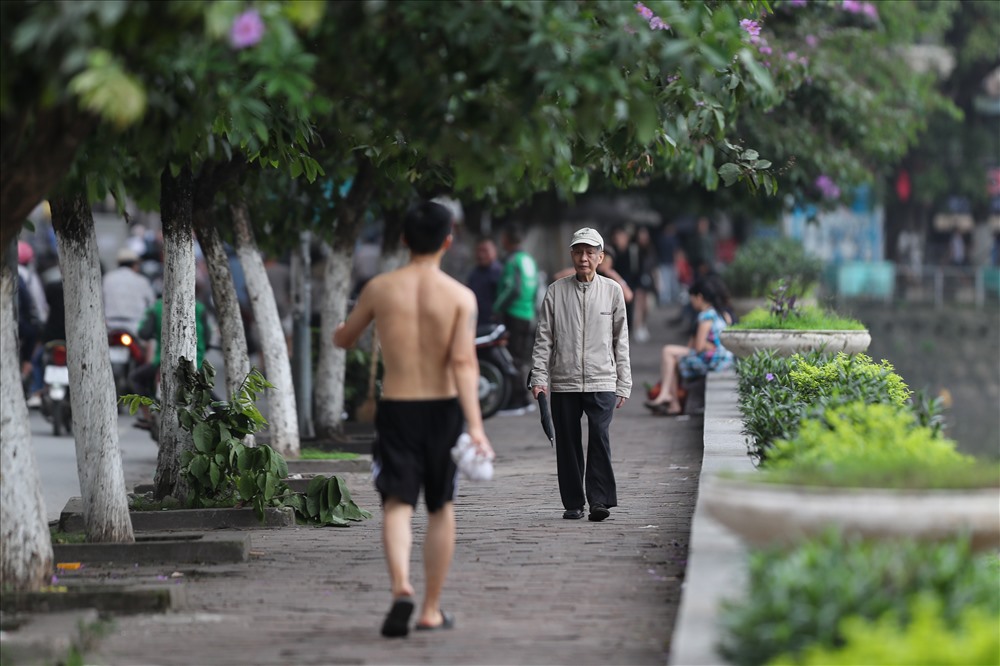 Những người già đi bộ dọc Hồ Gươm phải mặc thêm áo khoác.