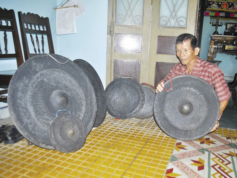 Ông Tại bên bộ cồng chiêng năm xưa còn giữ lại. Ông Tại bên bộ cồng chiêng năm xưa còn giữ lại.