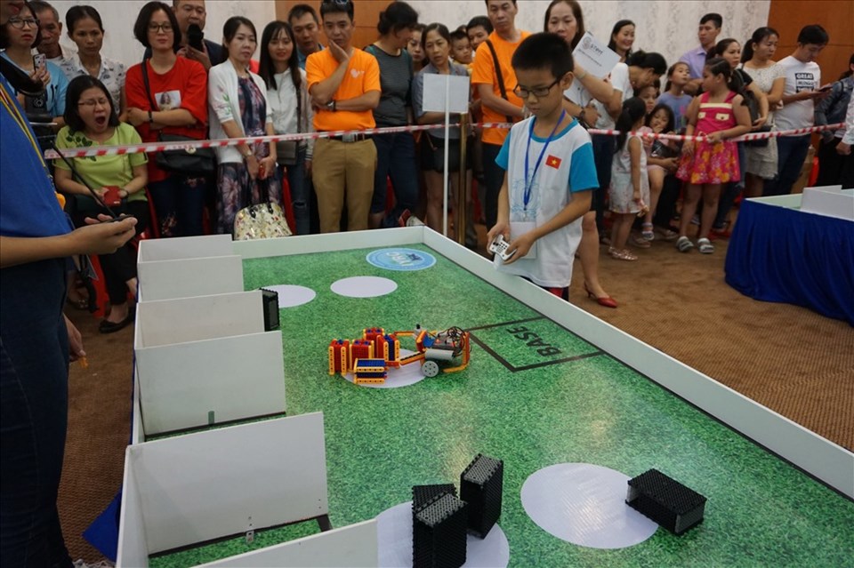 Các em học sinh điều khiển robot tham gia phần thi "tái chế vật liệu". Ảnh: M.Q Các em học sinh điều khiển robot tham gia phần thi "tái chế vật liệu". Ảnh: M.Q