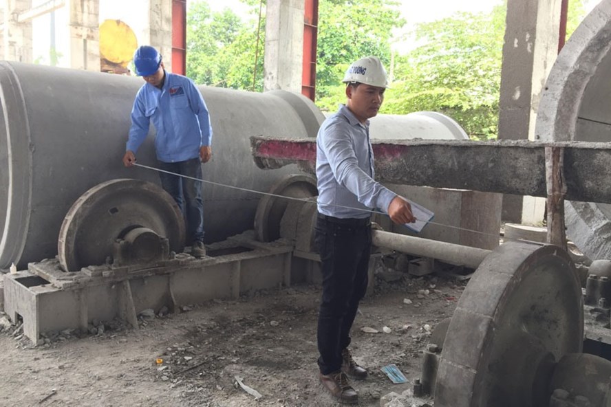 Kỹ sư Trần Quá»c Toản (phải) Äang cùng công nhân thao tác tại hiá»n trưá»ng.